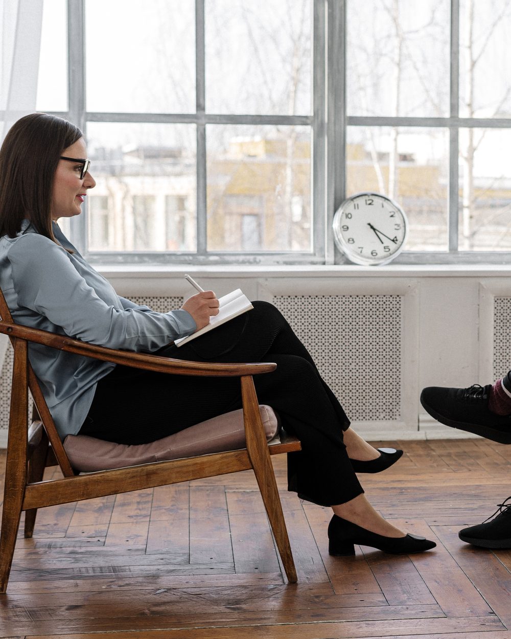 A professional in a calm coaching conversation, notebook in hand