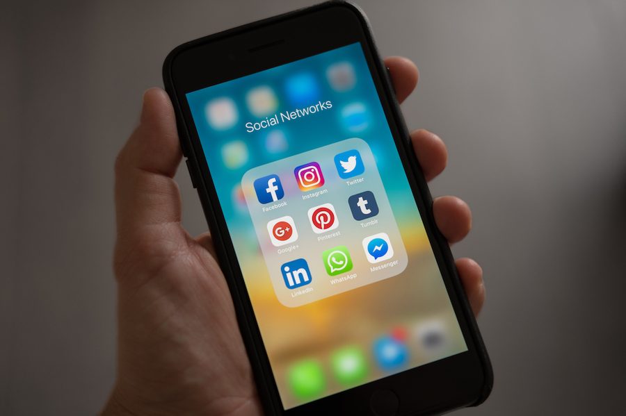 A hand endlessly scrolling social apps on a phone